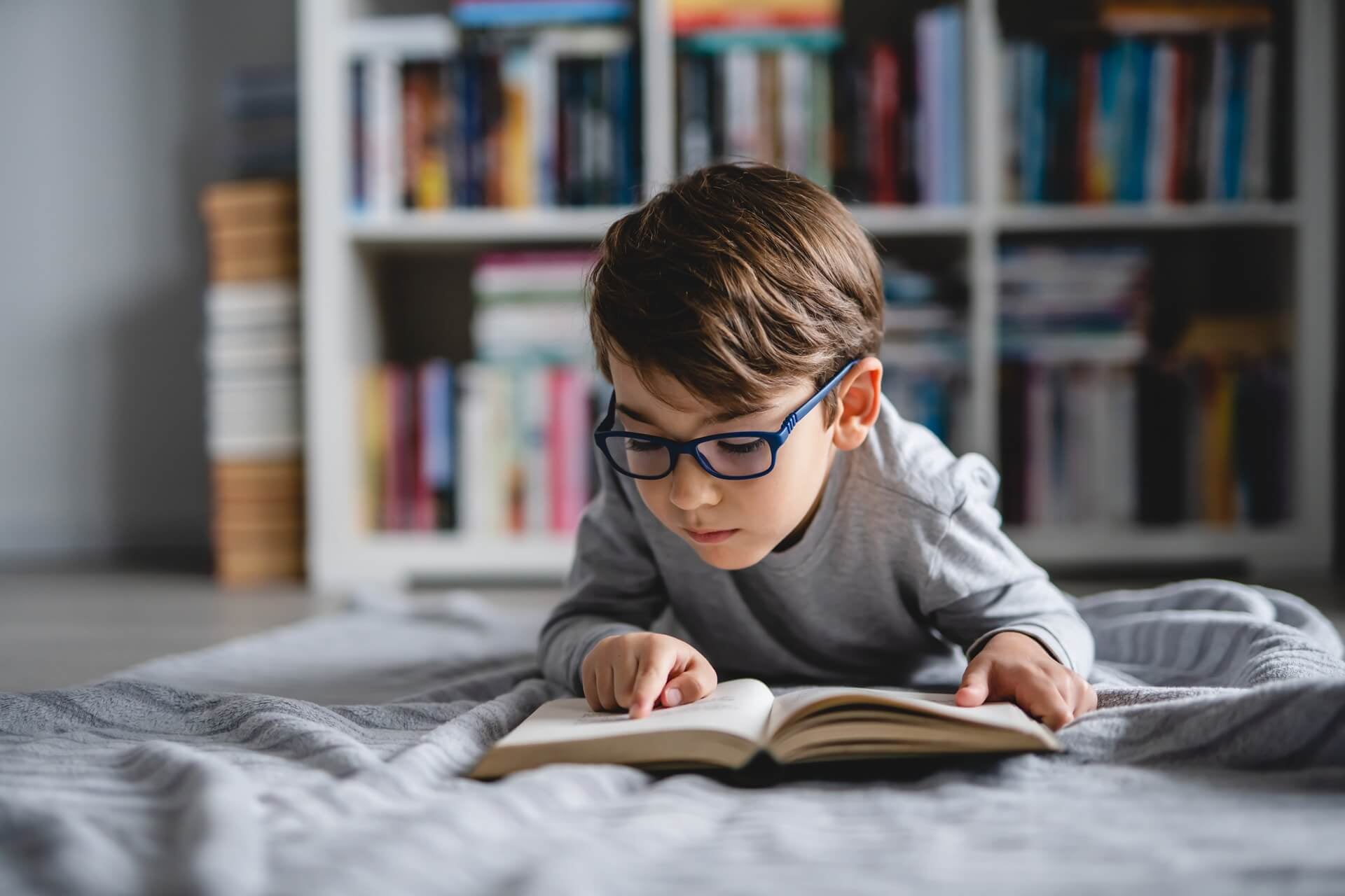A boy lying on the floor at home, reading a book.