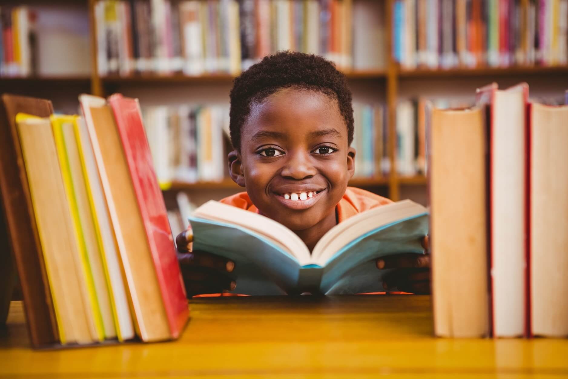 A small boy reading a book in the library.